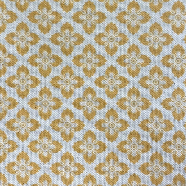 Muted spring-gold quatrefoils on a pale blue-grey woven textile