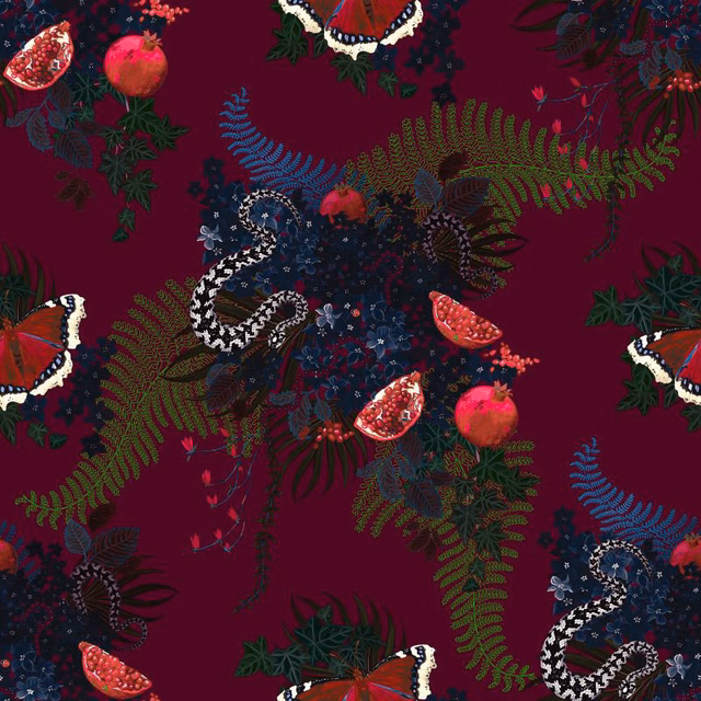 Deep crimson fabric showing coiled snakes, pomegranates, ferns and dark jewel-toned flowers.