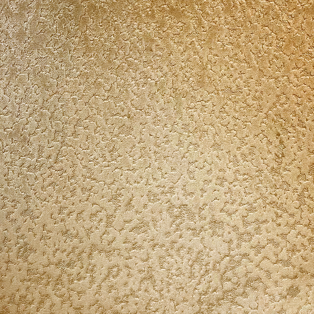 Warm bronze-gold fabric with irregular raised mottling and softly shimmering texture