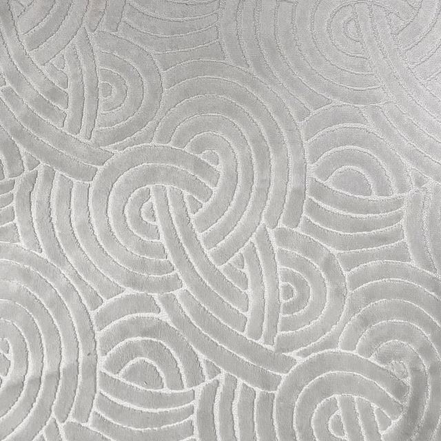 Pale dove-grey fabric with raised interlocking loops and paisley-like contours