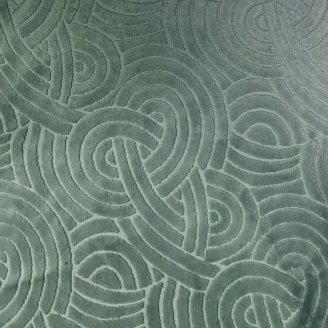 Muted forest green fabric with raised interlocking curved motifs and tactile tonal relief
