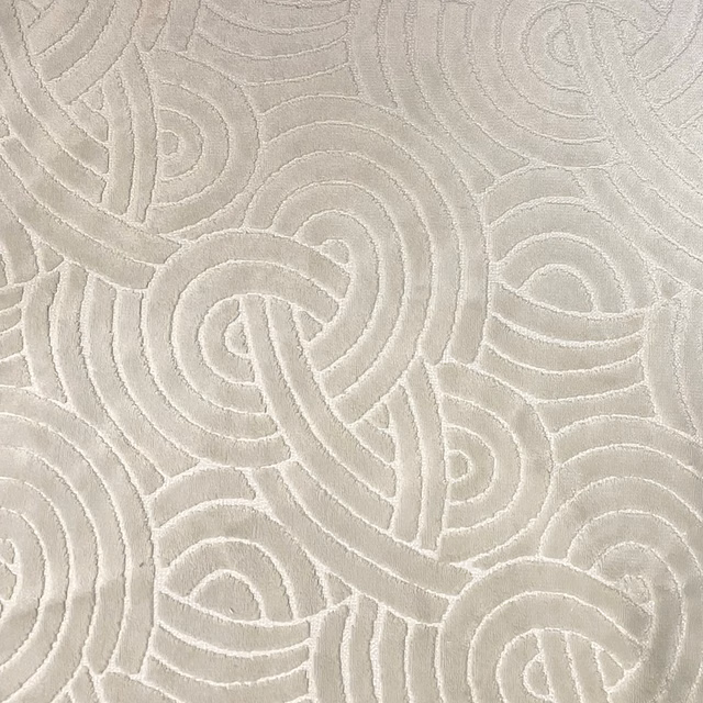 Pale oyster textile with raised interlocking paisley-like loops and a softly tactile surface