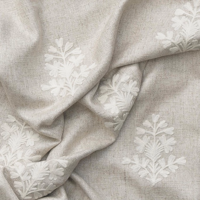 Pale ivory woven cloth with raised white botanical sprigs and soft folds