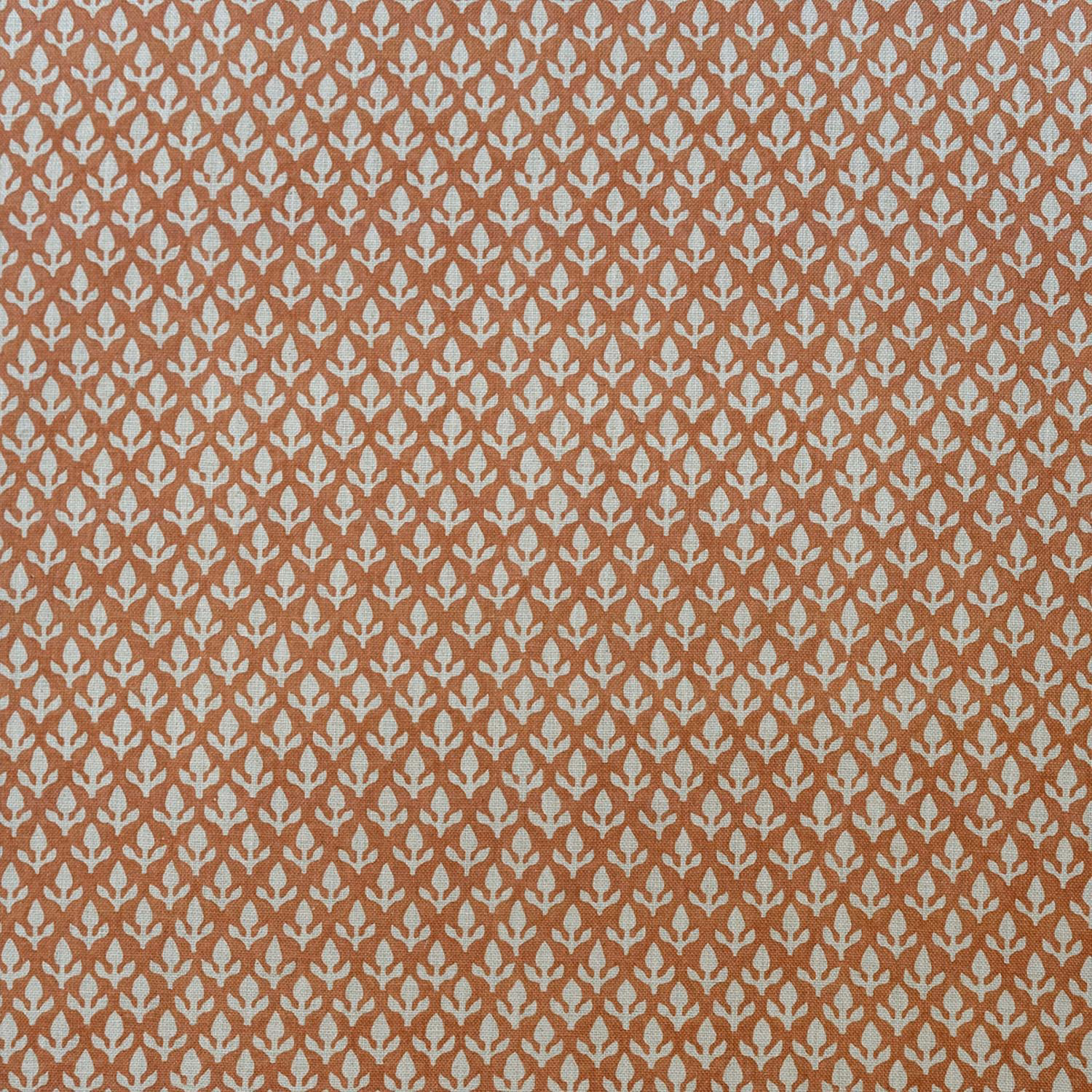 Burnt orange woven fabric with a small repeating cream bud motif