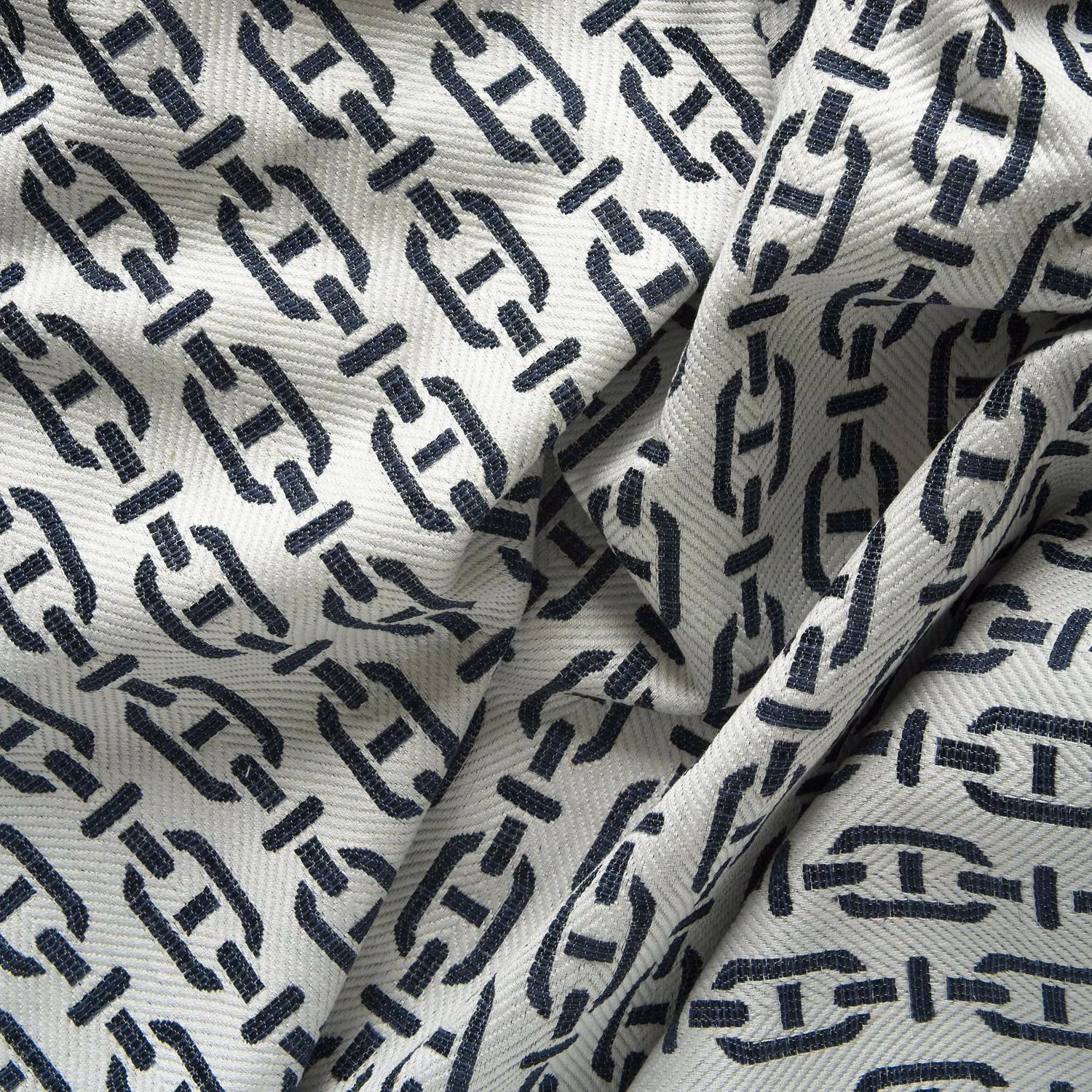 Deep navy geometric marks repeat across a ribbed ivory textile in soft folds