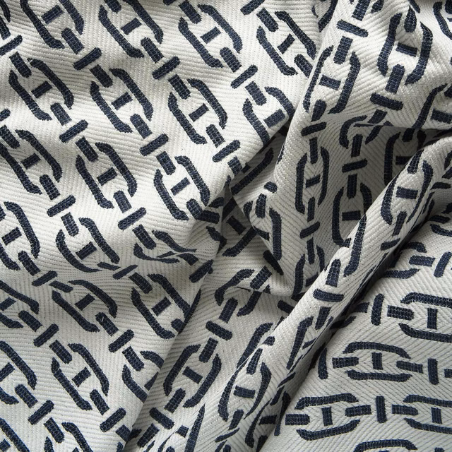 Deep navy geometric marks repeat across a ribbed ivory textile in soft folds