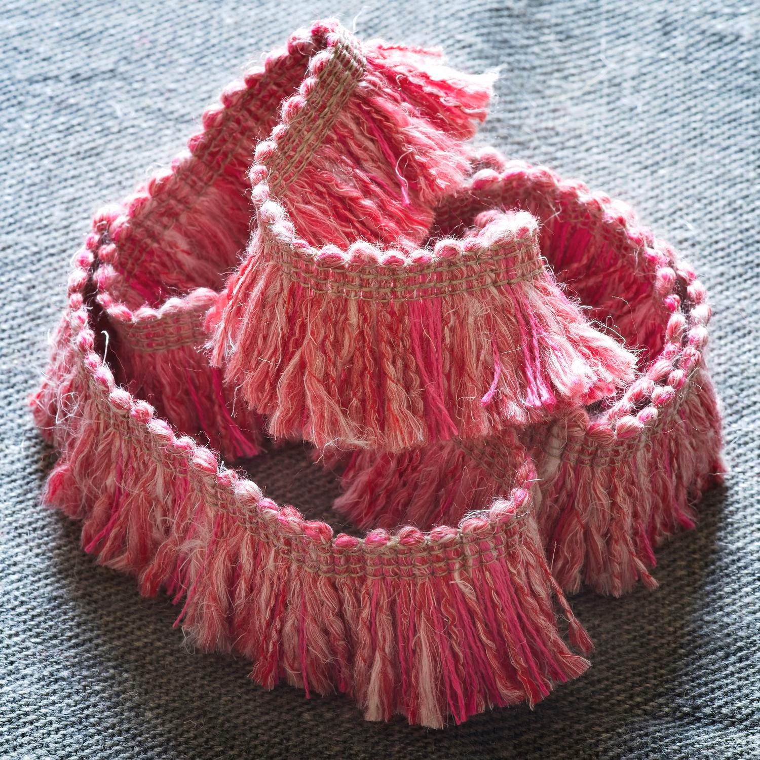 Raspberry pink fringe trim with shaggy strands and woven taupe edging
