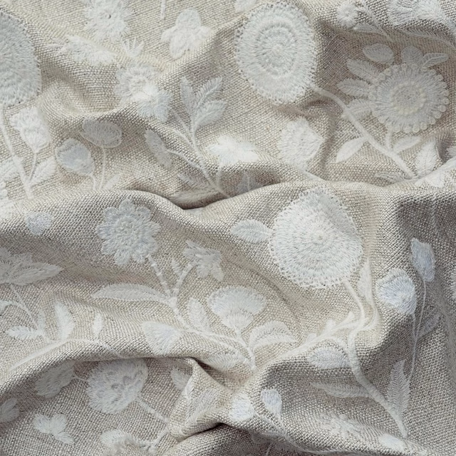 Ivory floral fabric with pale raised blossoms on a softly textured woven ground