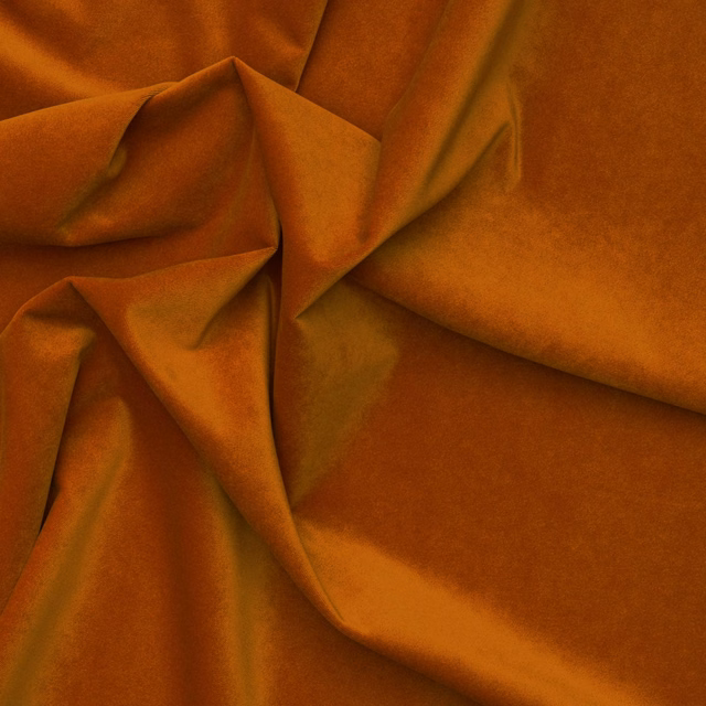 Burnt-orange outdoor velvet draped in folds, showing plush texture and amber highlights