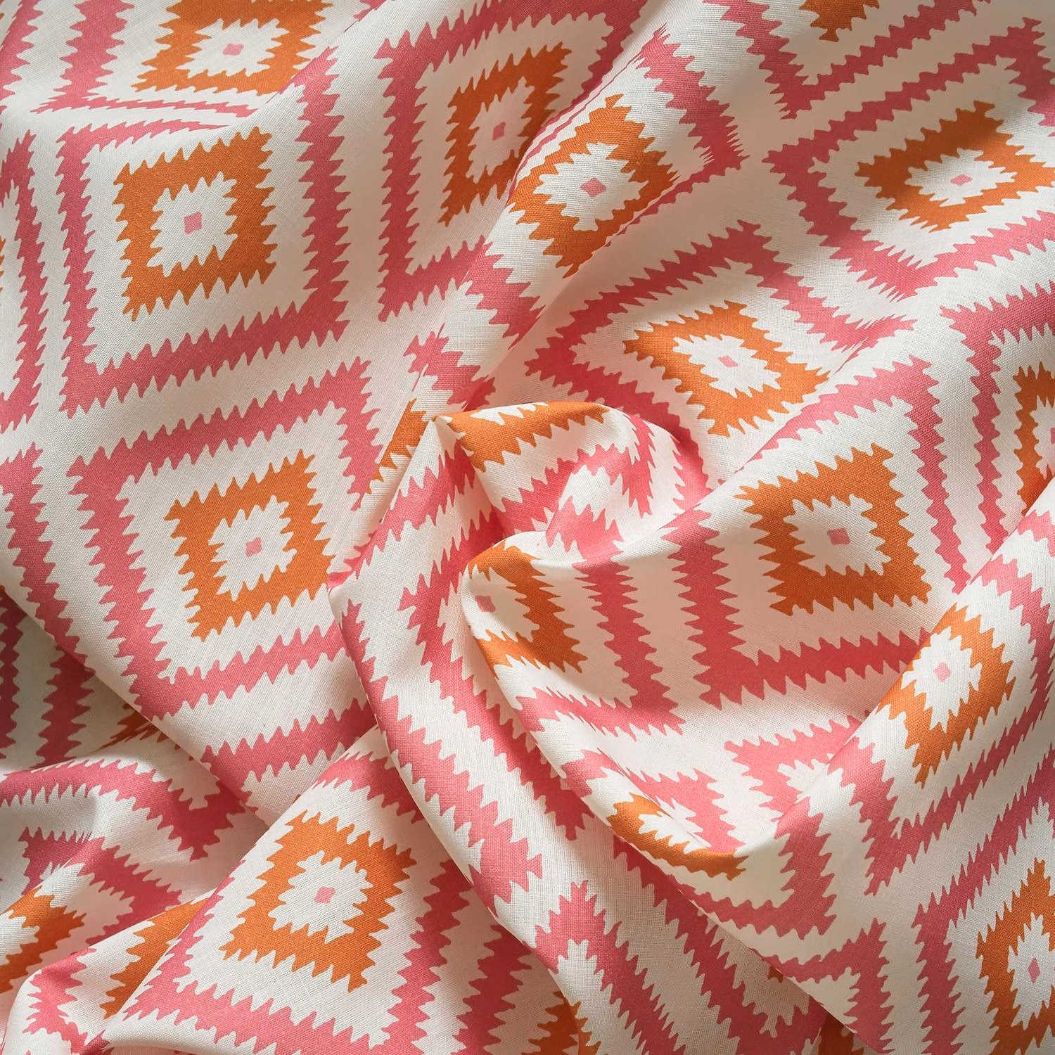 Coral pink and terracotta geometric diamond pattern on a cream outdoor fabric
