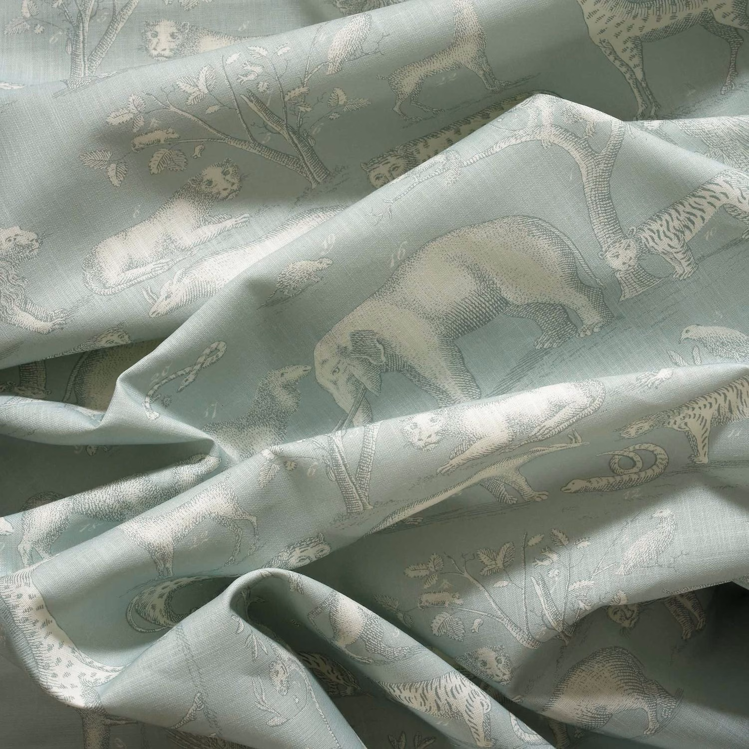 Pale icy sage woven fabric with ivory animal and botanical motifs