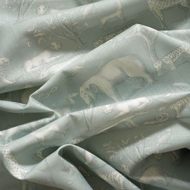 Pale icy sage woven fabric with ivory animal and botanical motifs