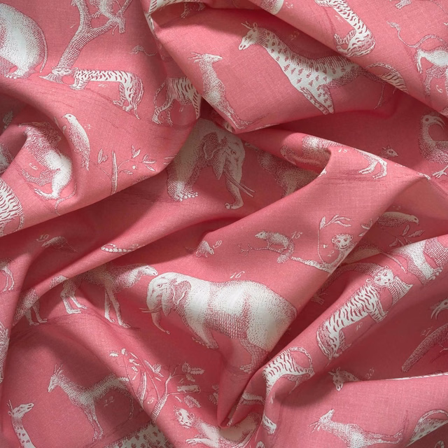 Dusty rose outdoor fabric with pale illustrated animals and softly textured folds