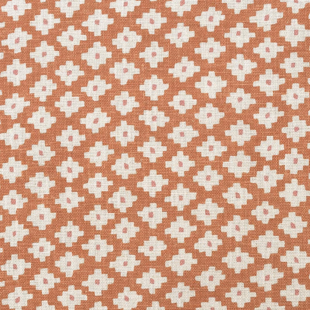 Muted terracotta orange woven fabric with repeated cream cross motifs