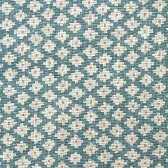 Textured turquoise cloth with repeated cream four-lobed flowers and tiny ochre centres