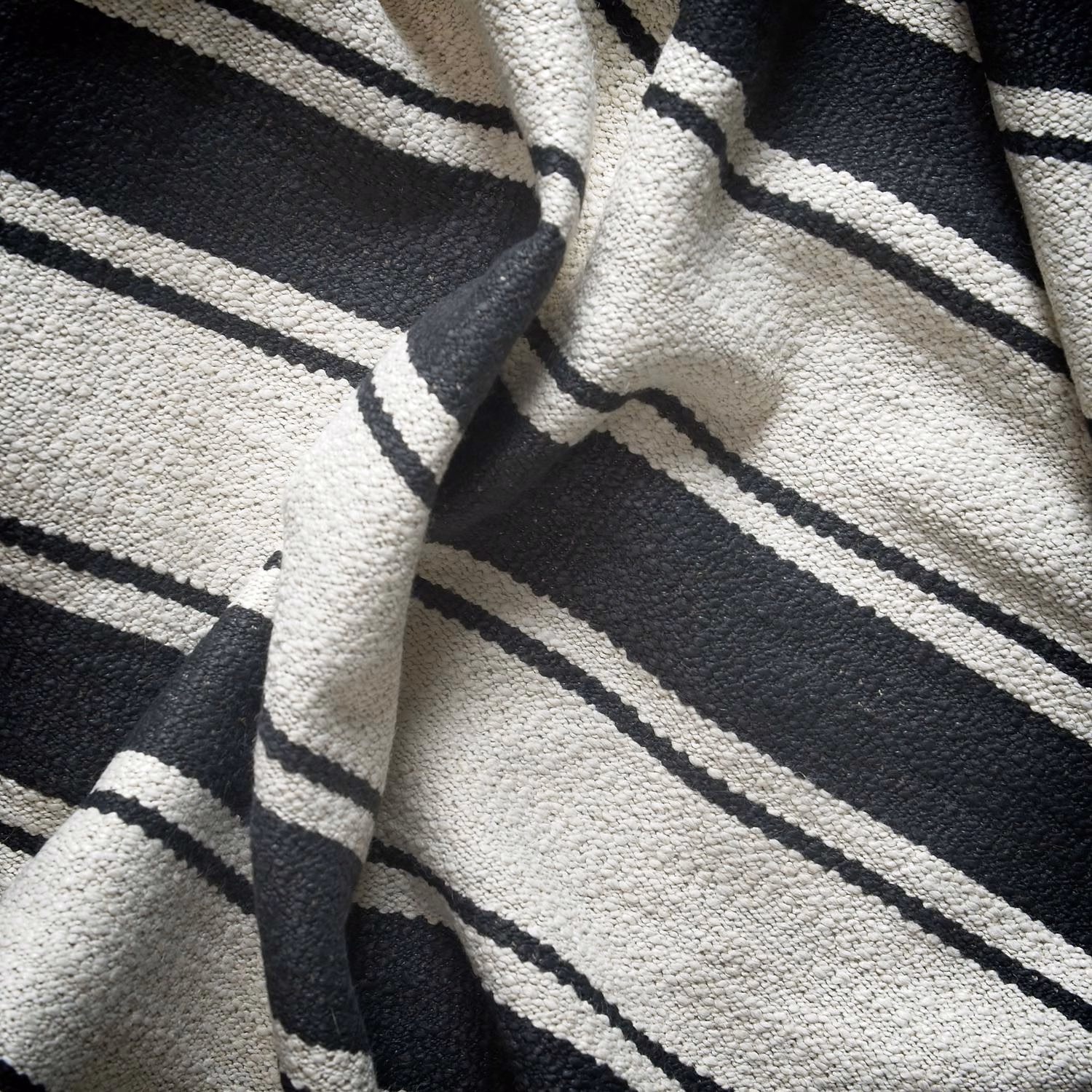 Textured black and ivory woven fabric with irregular sloping stripe bands