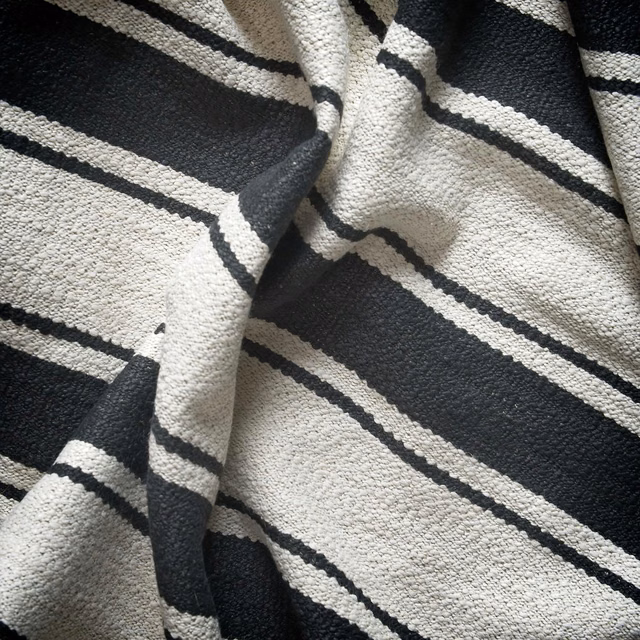 Textured black and ivory woven fabric with irregular sloping stripe bands