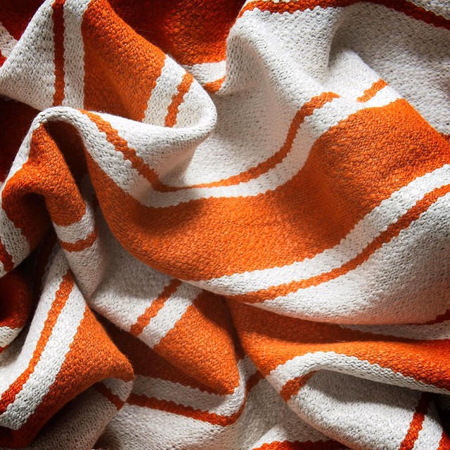 Chunky woven fabric in vivid orange and cream with broad irregular stripes
