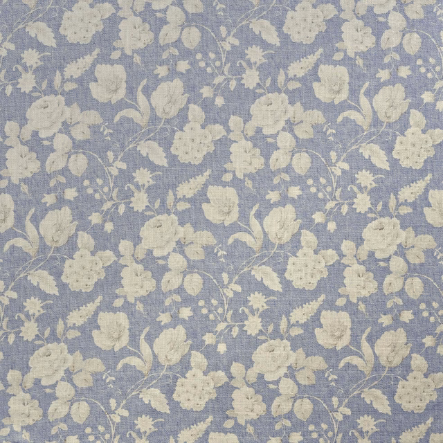 Muted denim-blue woven fabric with a pale cream floral and leafy botanical repeat