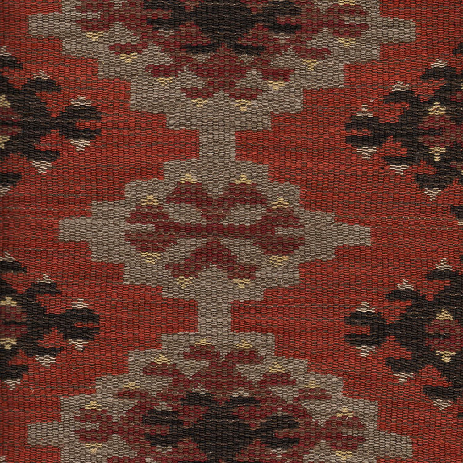 Brick-red woven fabric with stepped stone motifs and dark floral accents