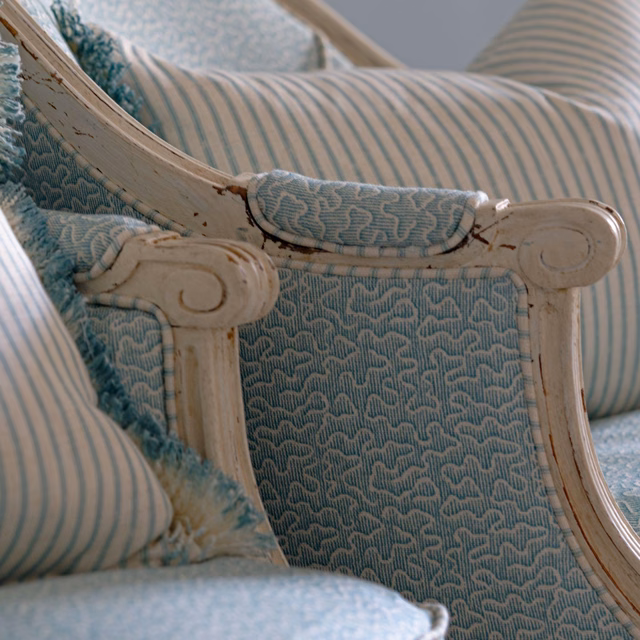 Muted turquoise woven upholstery with small wave motifs on an ornate carved chair