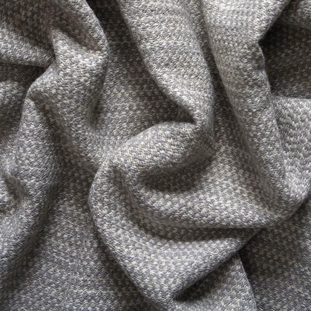 Mottled cool-grey woven fabric folded into deep, softly textured sculptural pleats