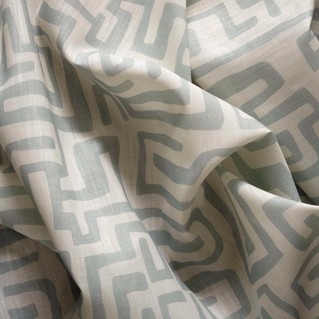 Pale ice-blue and grey abstract geometric lines across softly folded ivory fabric