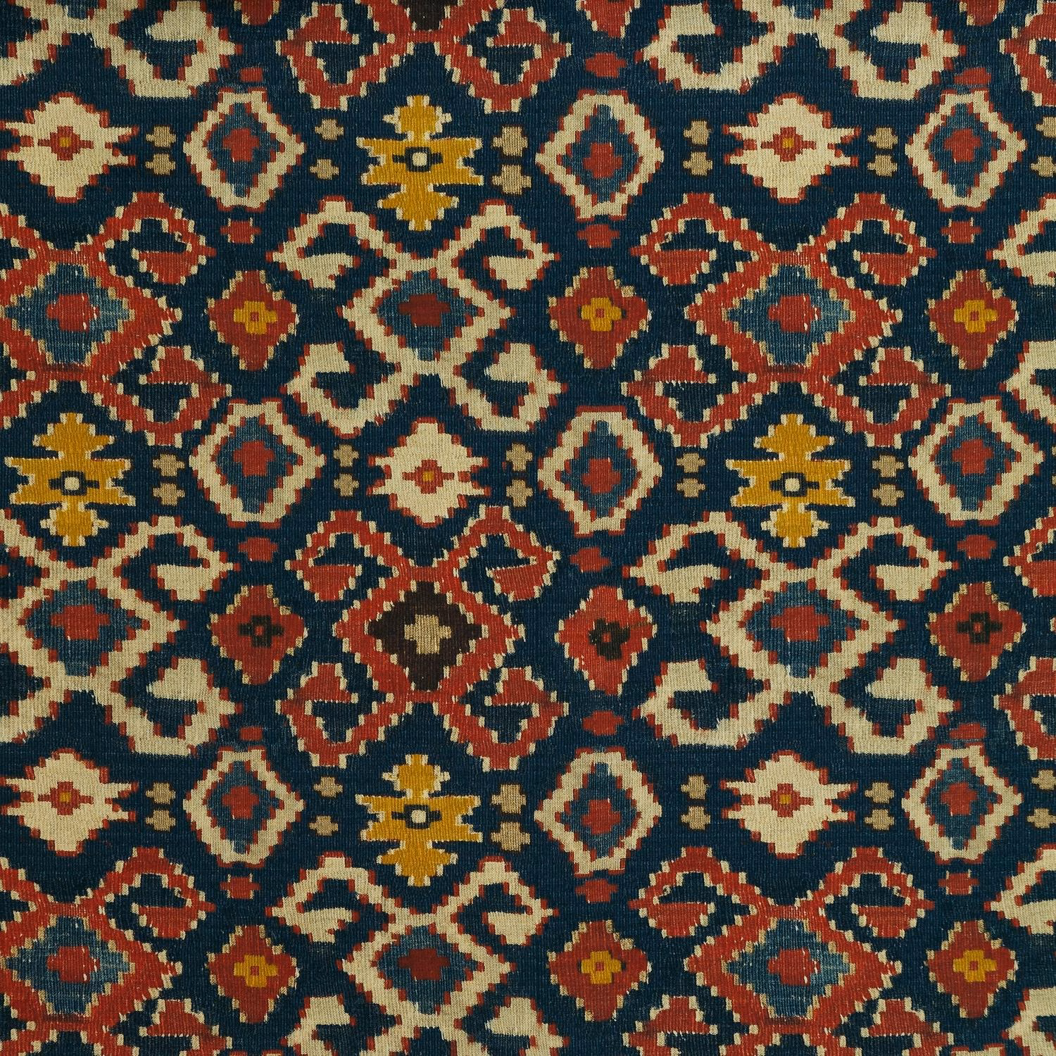 Dense woven geometric fabric in deep teal, rust, cream and ochre
