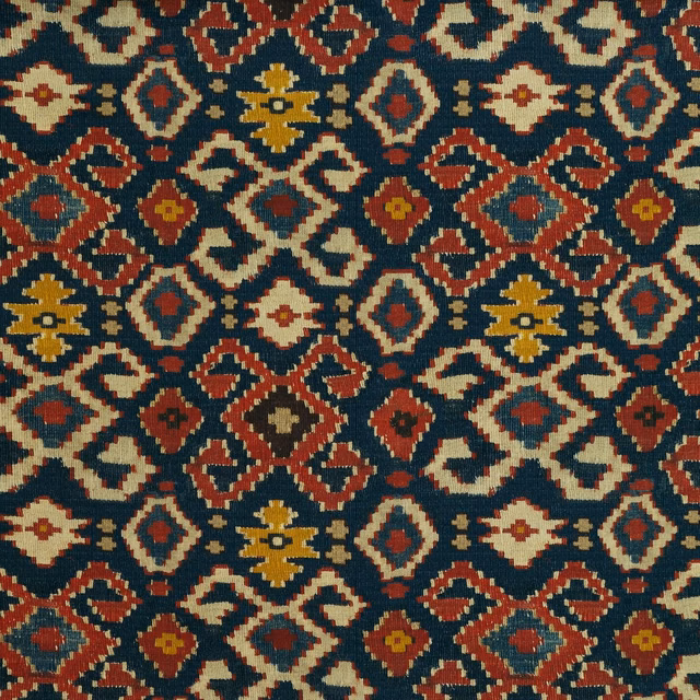 Dense woven geometric fabric in deep teal, rust, cream and ochre