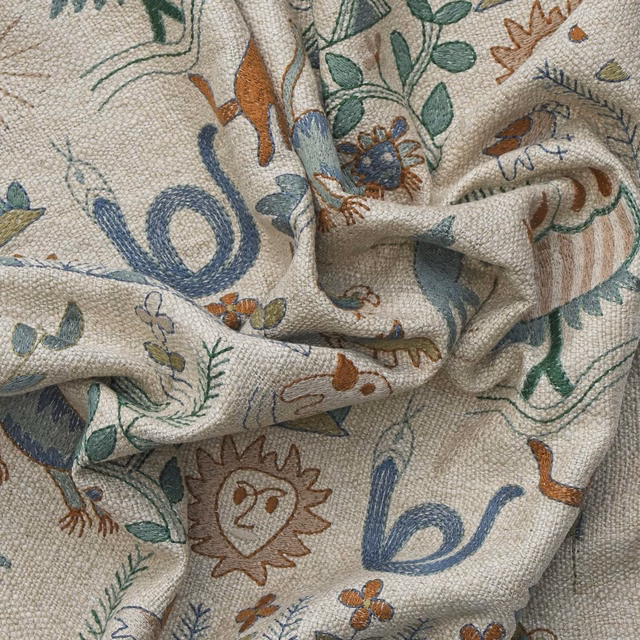 Cream woven fabric with forest leaves, blue serpents and rust animal motifs