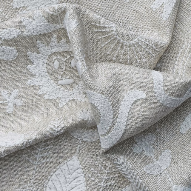 Warm ivory greige fabric with raised chalky botanical motifs and a tactile woven texture