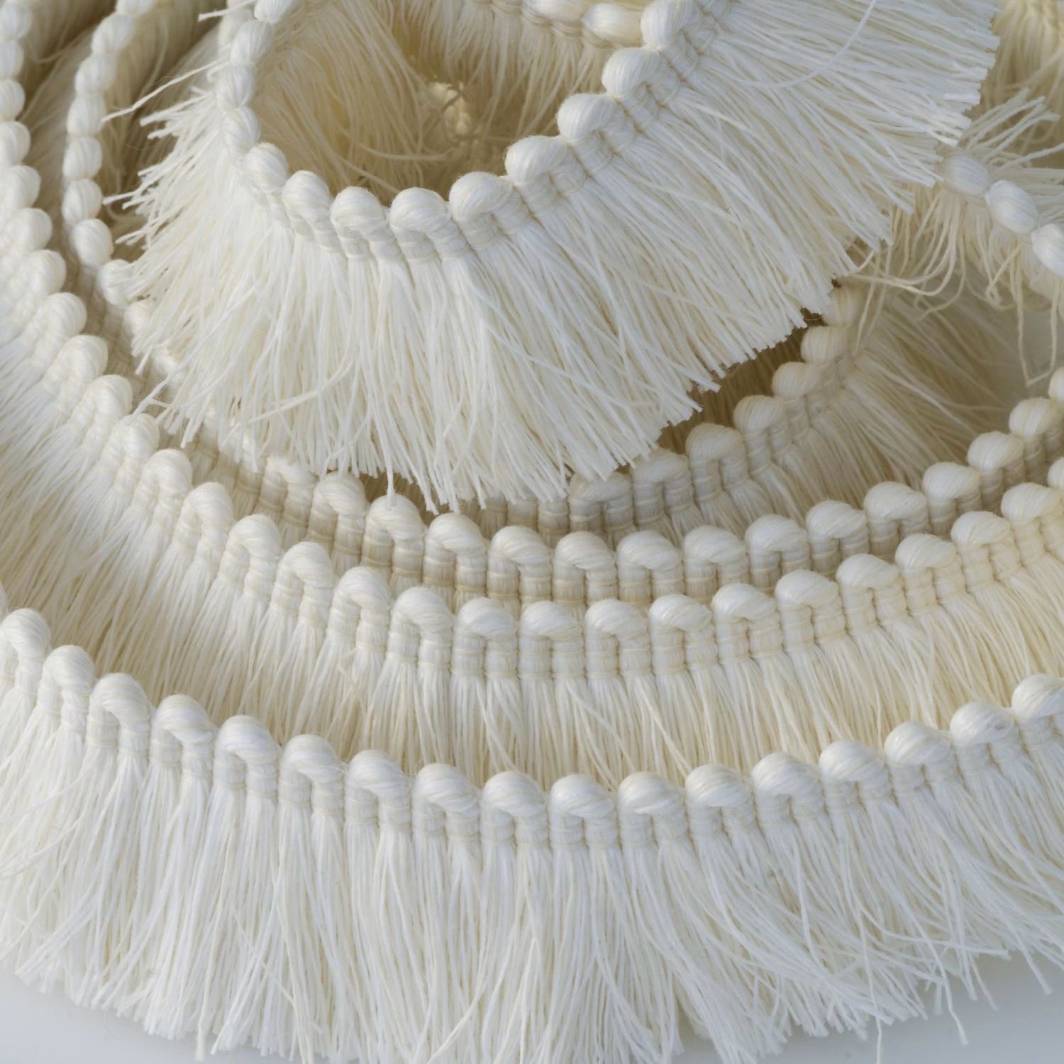 Ivory layered fringe trim with rounded corded rows and loose tassel texture