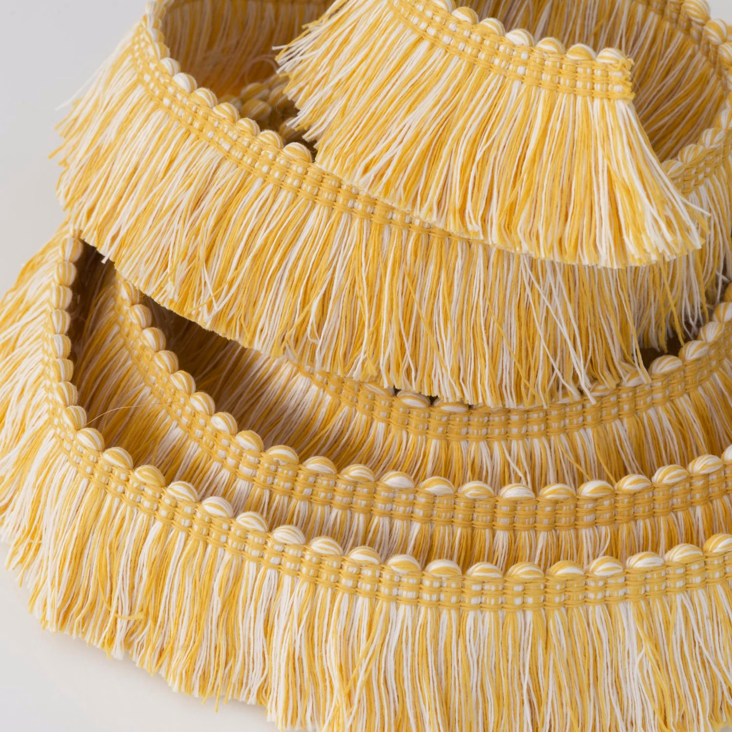 Warm golden-yellow outdoor trim with cream fringe and rounded braided rows
