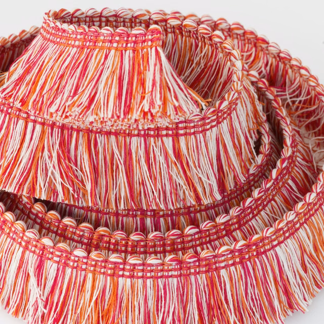 Raspberry red and ivory tassel trim with orange strands and braided bands