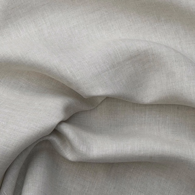 Pale natural beige cloth with fine herringbone weave gathered into soft fluid folds