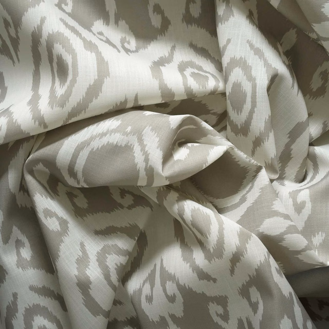 Pale sage-grey outdoor fabric with cream ikat scrolls and a softly textured weave