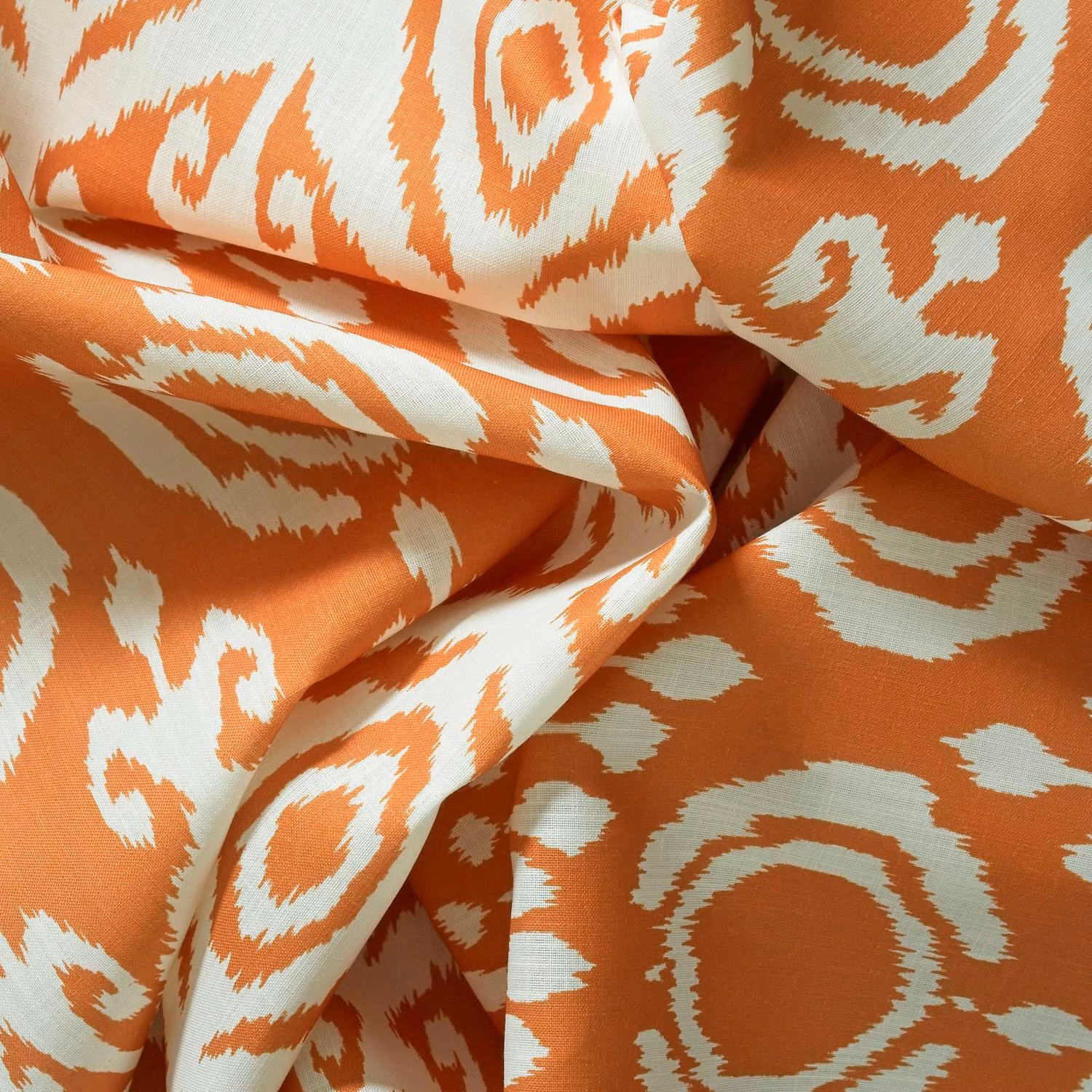 Terracotta orange woven fabric with cream ikat-style rings and angular motifs