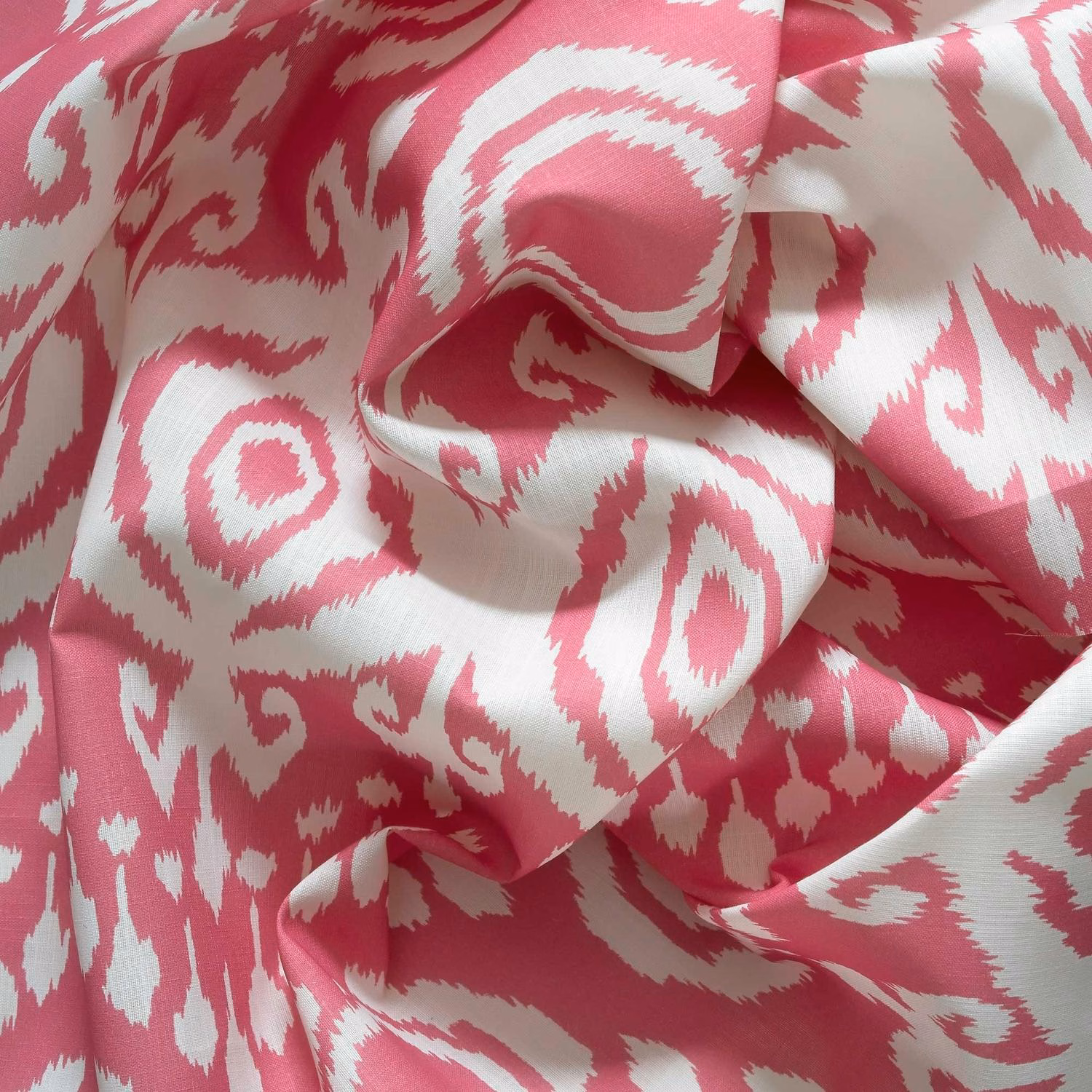 Rose pink and ivory woven fabric with bold abstract ikat swirls and soft folds