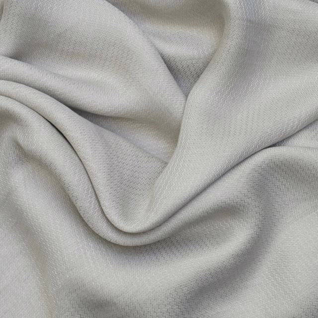 Pale sage-grey fabric draped in folds with a fine miniature chevron weave