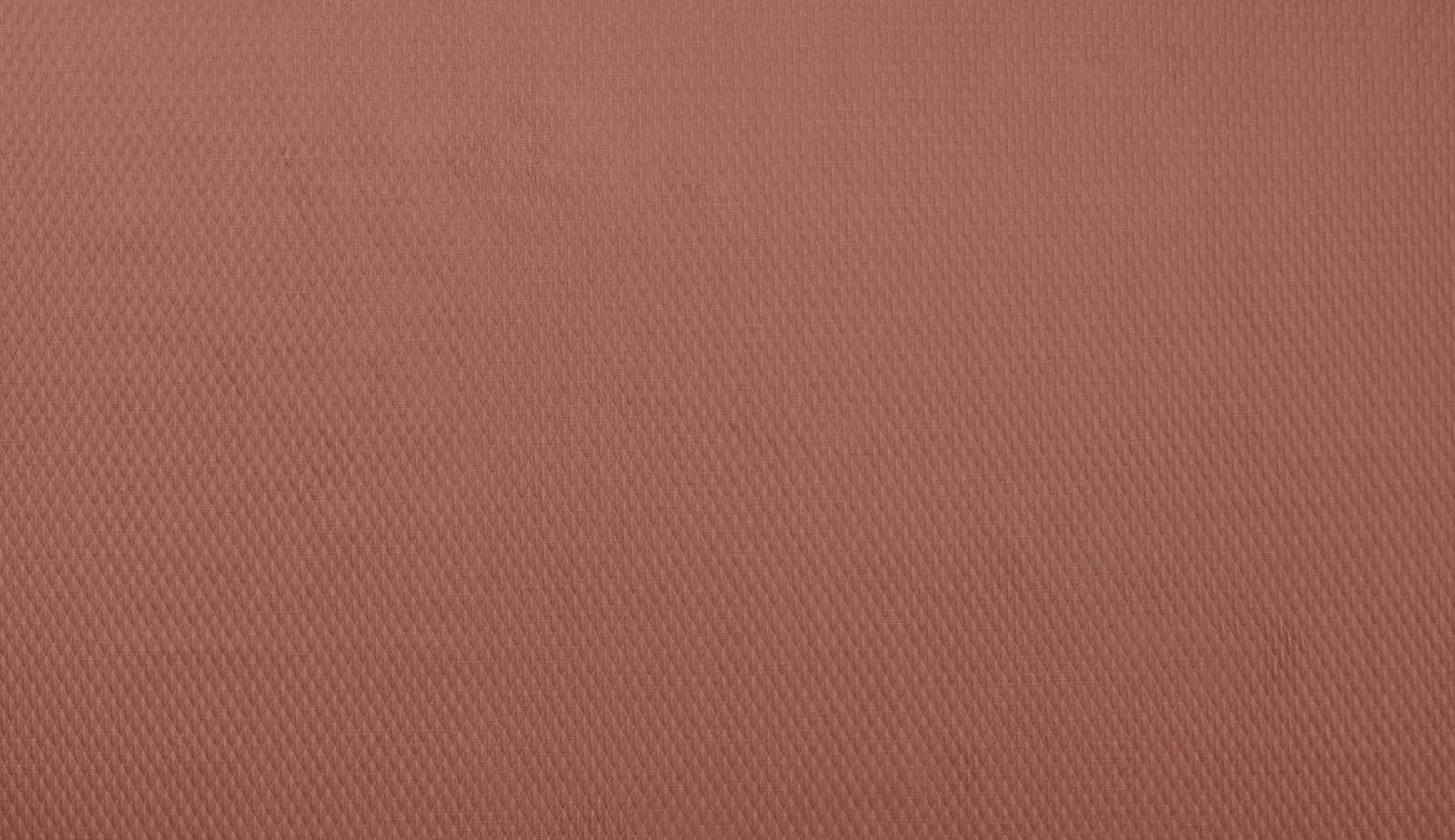 Close-up of a soft coral terracotta woven fabric with fine textured diagonal pattern