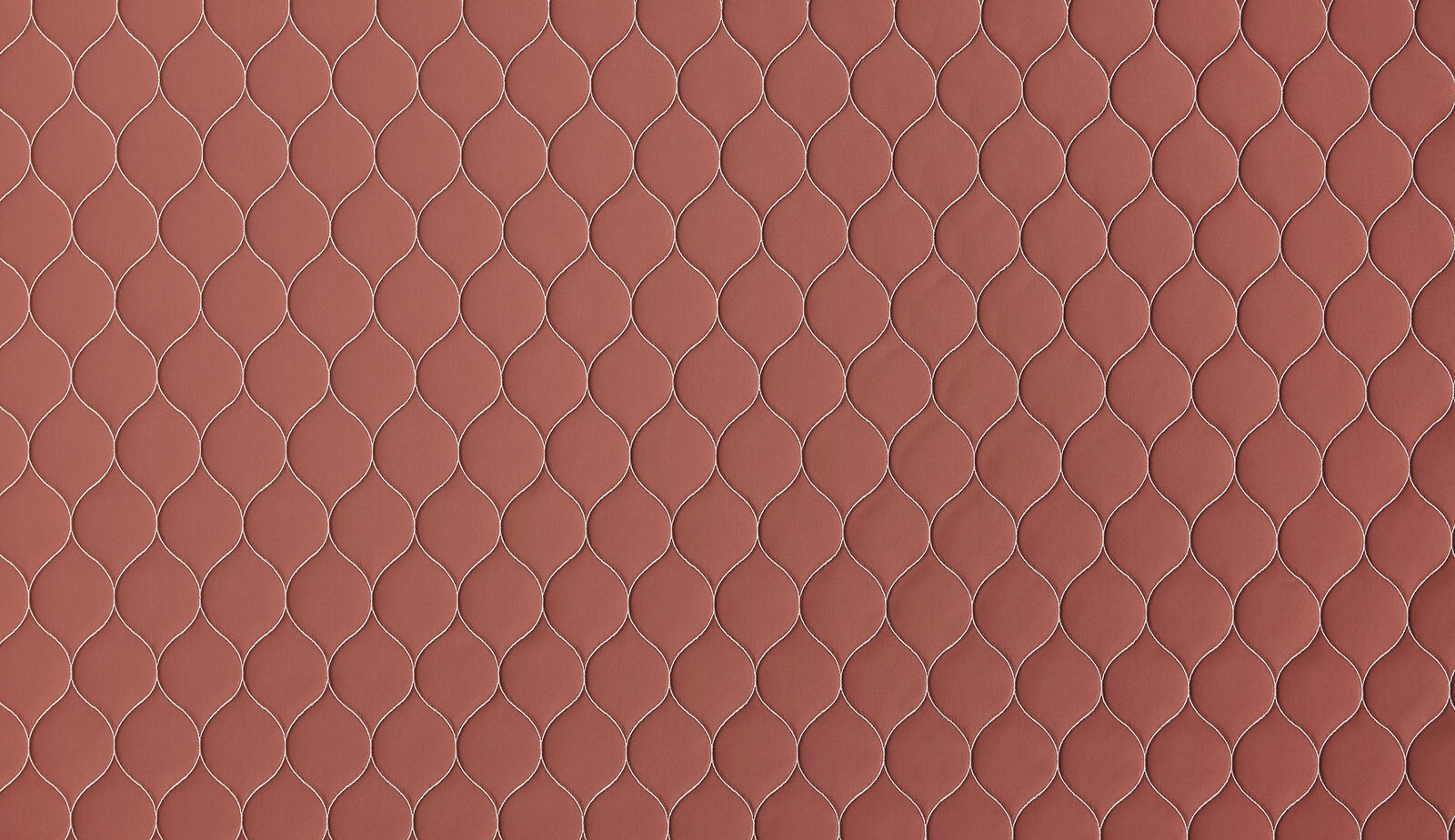 Muted coral terracotta fabric with a small looped lattice pattern