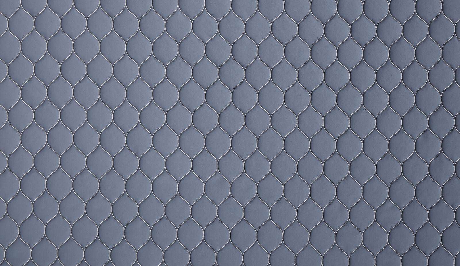 Close-up of muted slate-blue woven fabric with small repeating linked motif
