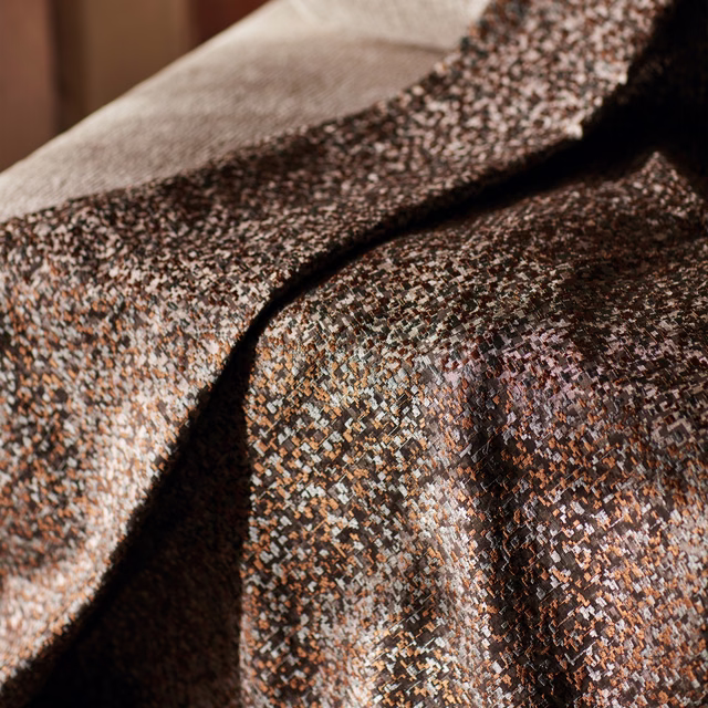 Rosewood-brown woven fabric with tiny geometric flecks in copper, cream and blue