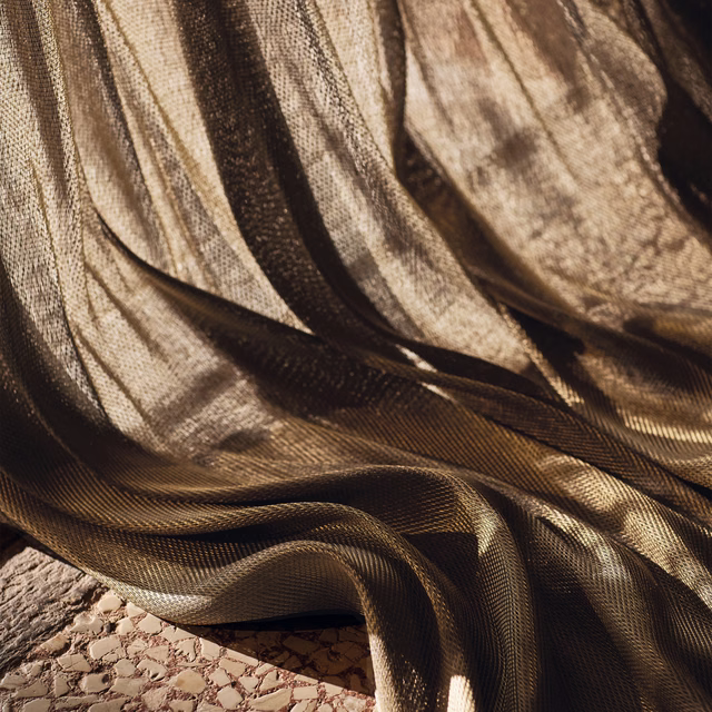 Bronze-brown fine weave falling in fluid folds over a textured surface