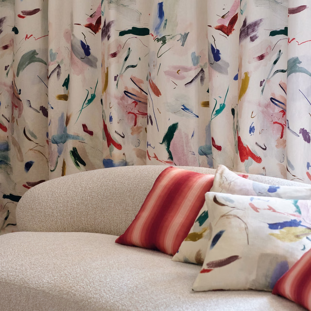 Warm ivory textile with scattered red, blue, teal and burgundy painterly marks