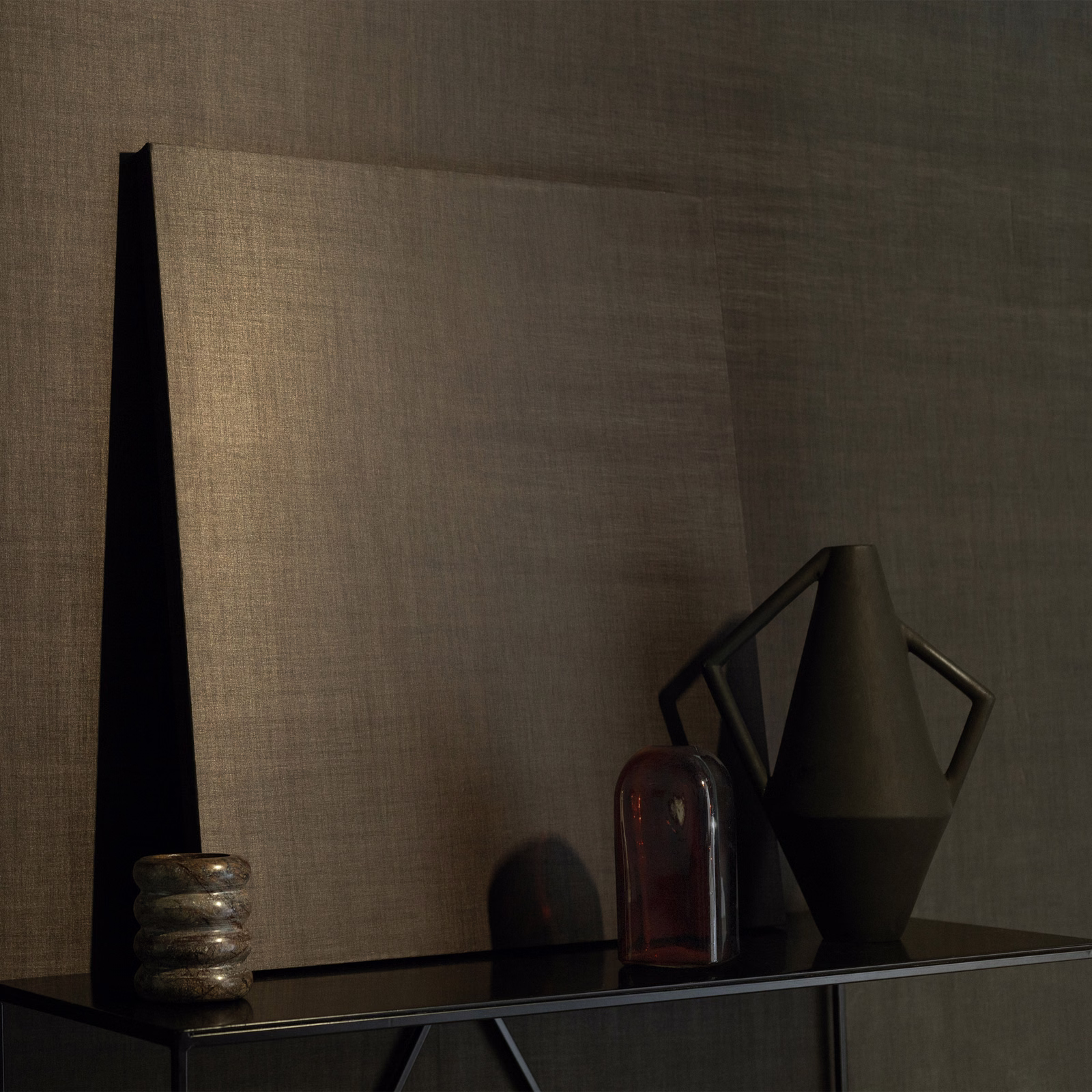 Warm taupe Tonka wallpaper with fine woven texture on a softly lit wall