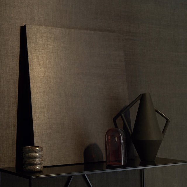 Warm taupe Tonka wallpaper with fine woven texture on a softly lit wall