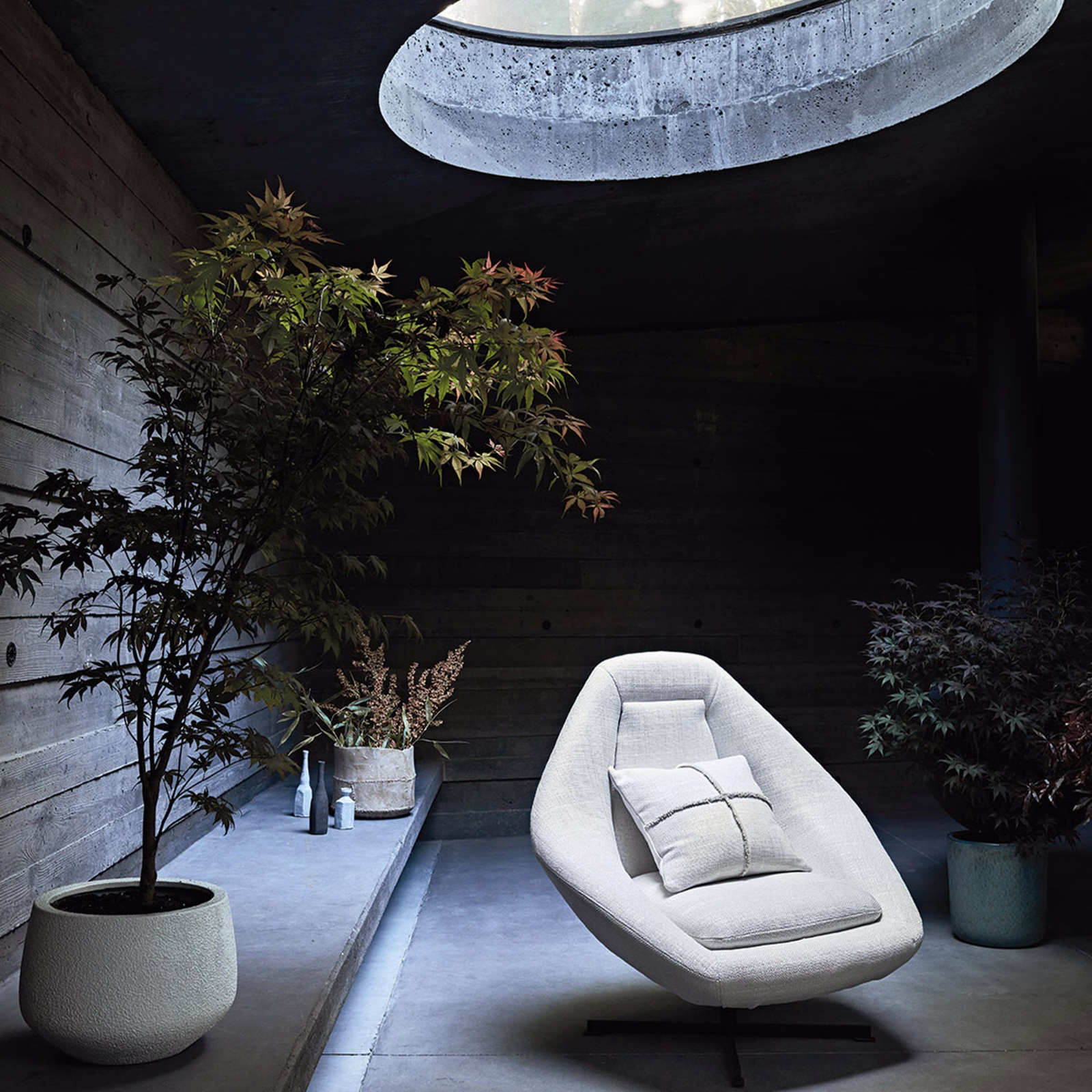 Cool whitewash textured upholstery on a sculptural lounge chair in a dark timber room