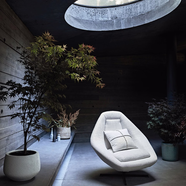 Cool whitewash textured upholstery on a sculptural lounge chair in a dark timber room