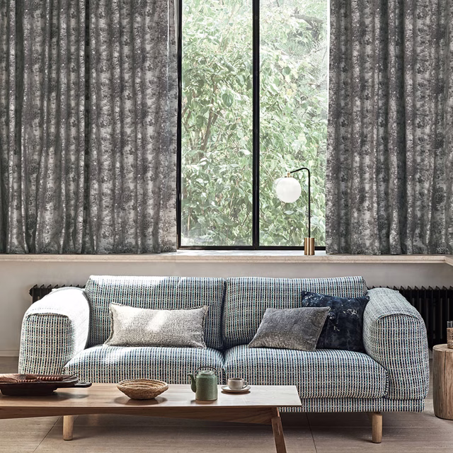 Charcoal-grey curtains with pale mottled vertical striations beside a tall window